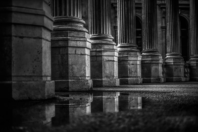 Colonnes du Palais Longchamp à Marseille photographiées après la pluie avec reflets sur le sol détrempé.