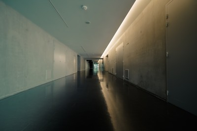 Couloir intérieur du Mucem à Marseille avec béton brut, sol sombre réfléchissant et lumière architecturale linéaire