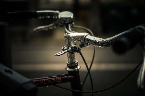 Guidon de vélo avec gouttes d’eau sur le chrome, photographié de près à Marseille, avec un arrière-plan sombre et flou.