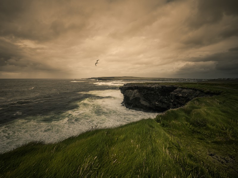 Falaises des Kilkee Cliffs en Irlande avec océan Atlantique agité, écume blanche, rochers sombres et ciel chargé dans le comté de Clare