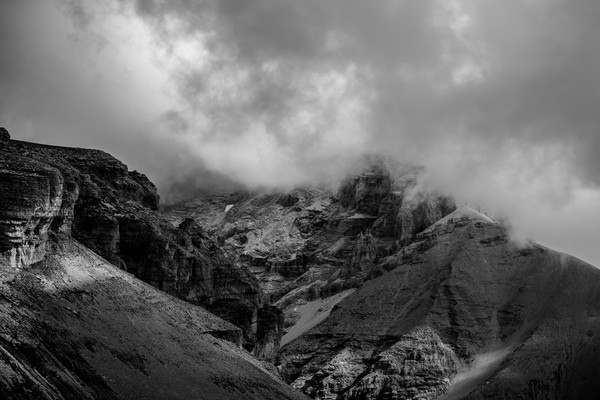 Montagne rocheuse des Hautes-Alpes enveloppée par des nuages bas dans une atmosphère minérale