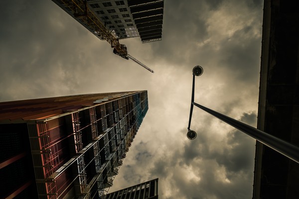 Tour La Marseillaise à Marseille photographiée en contre-plongée sous un ciel nuageux, avec une grue et un lampadaire dans le quartier Euroméditerranée