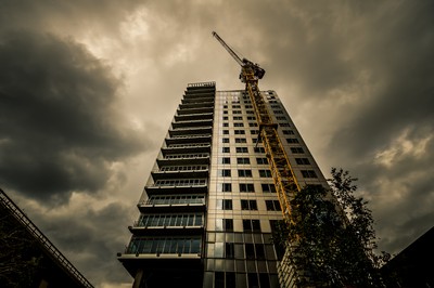 Tour Le Mirabeau à Marseille photographiée en contre-plongée pendant sa construction, avec une grue de chantier et un ciel sombre au-dessus du quartier Euroméditerranée.