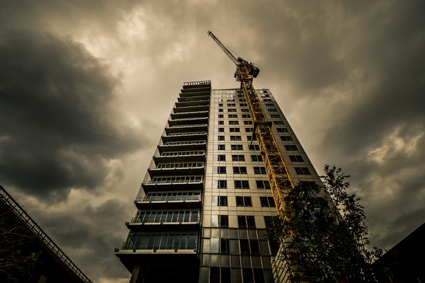 Tour Le Mirabeau à Marseille photographiée en contre-plongée pendant sa construction, avec une grue de chantier et un ciel sombre au-dessus du quartier Euroméditerranée.
